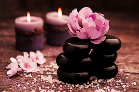 hot stones in massage oil, with pink flowers and candles