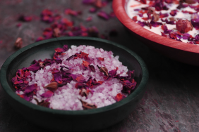dried flower petals in a bowl of deeply exfoliating pink sugar or Himalayan salt scrub